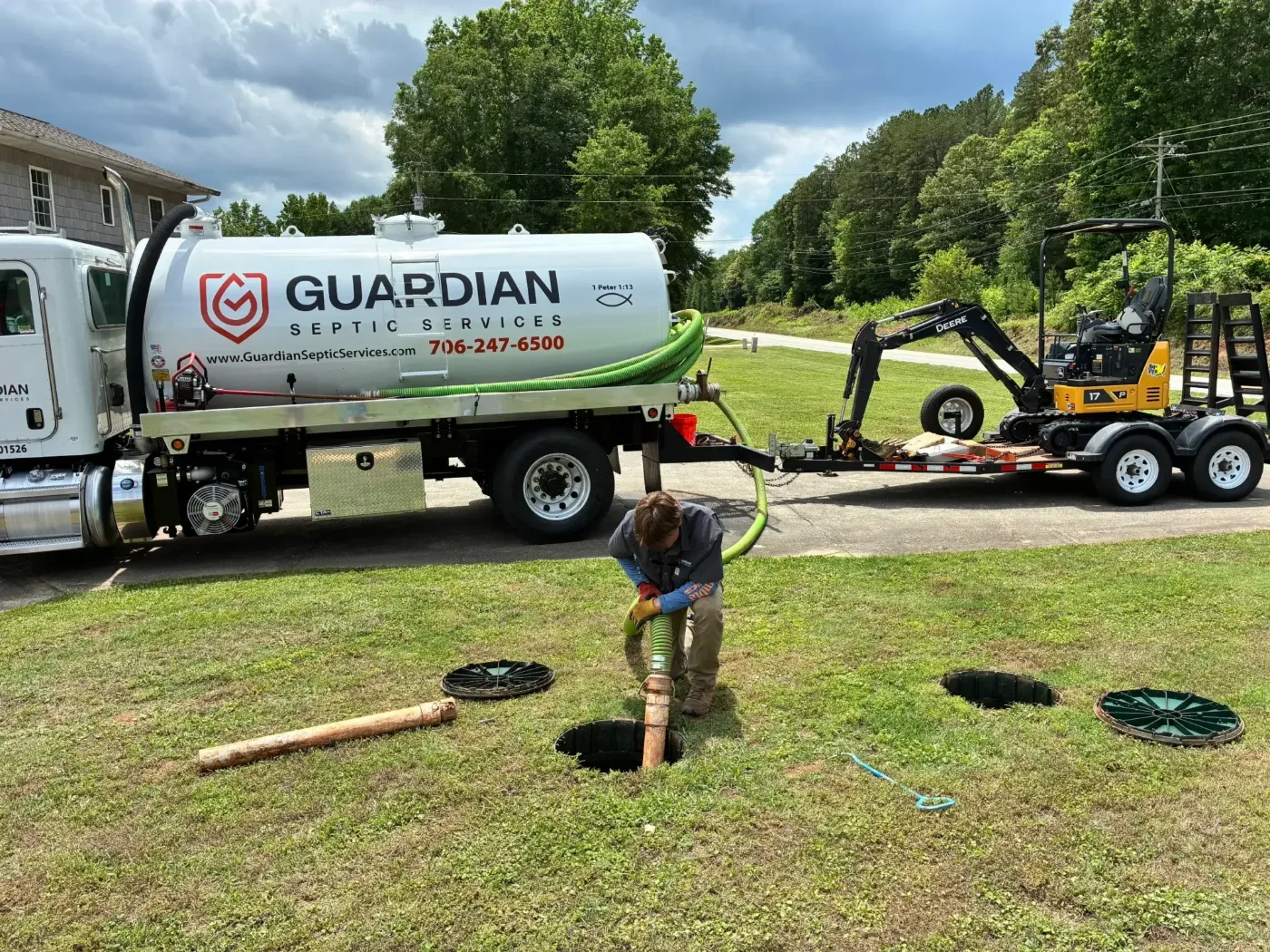 A Guardian technician pumping a residential septic tank beside the vacuum truck
