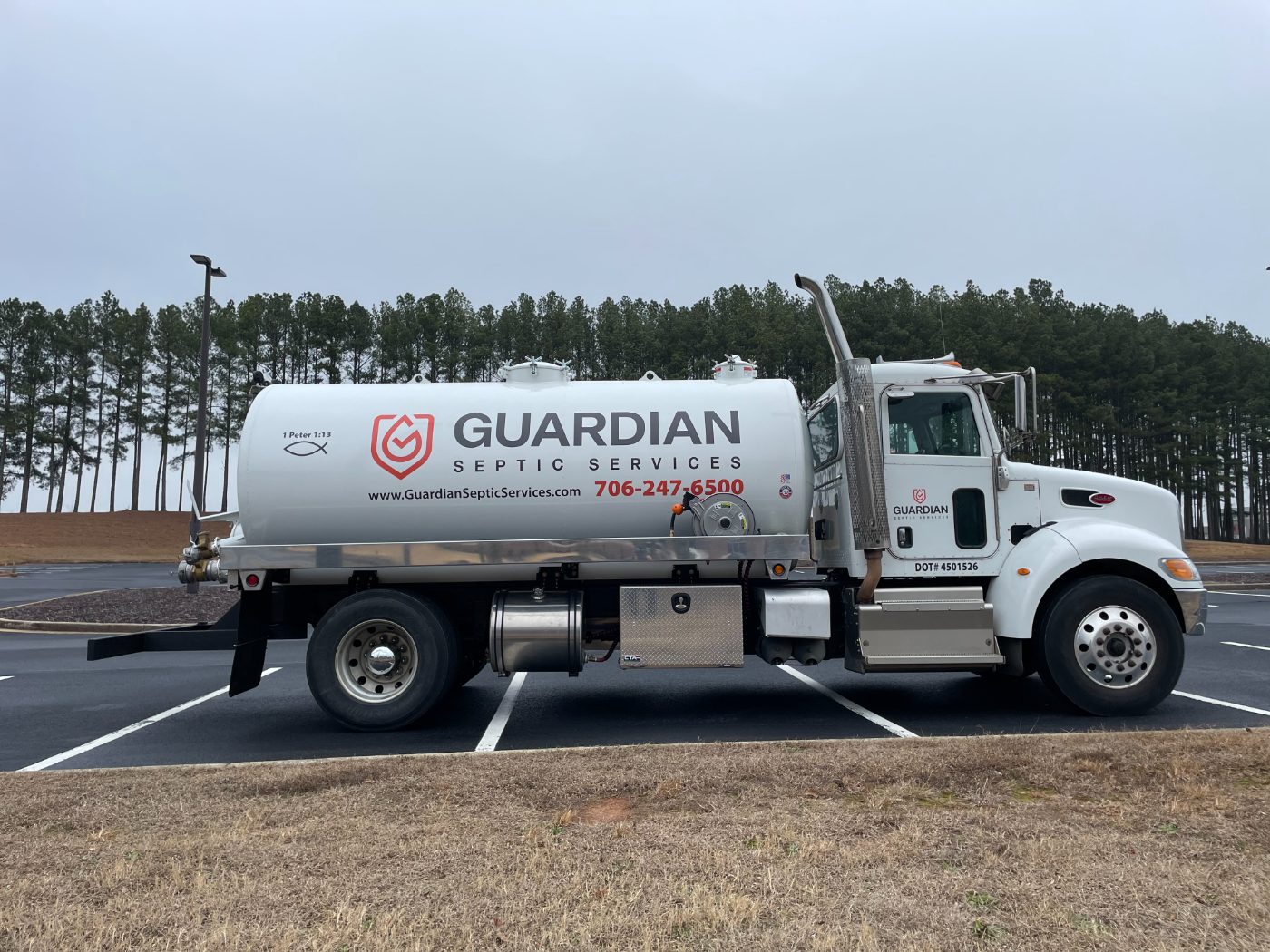 A Guardian Septic Services vacuum truck showing the company name and phone number